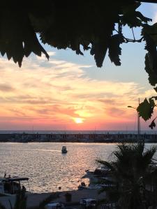 un barco en un cuerpo de agua al atardecer en Kale Motel, en Gokceada Town