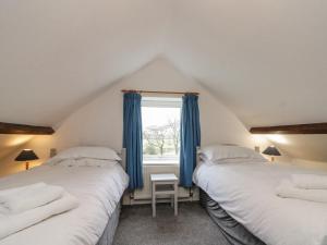 two beds in a attic bedroom with blue curtains at Orchard Cottage in Whitby