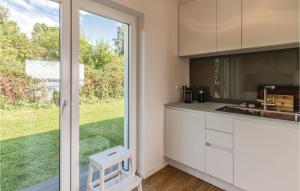 eine Küche mit weißen Schränken und einer Glasschiebetür in der Unterkunft Cozy Home In Bosau With Kitchen in Bosau