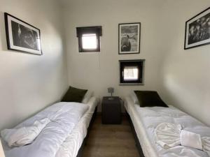 2 camas en una habitación con sábanas blancas en Tiny vakantiehuis aan het water met eigen steiger en airco, en Kampen
