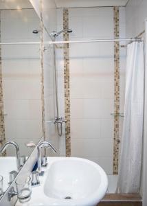 y baño blanco con lavabo y ducha. en La Tiasta en Maipú