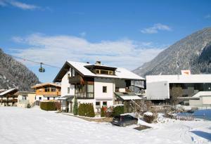 een huis in de sneeuw naast een berg bij Haus Viktoria in Mayrhofen