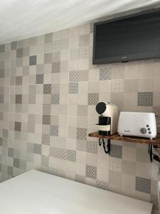 een kamer met een tv aan een betegelde muur bij Quintinha da Cachadinha in Ponte de Lima