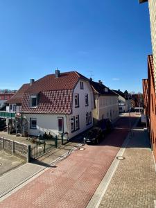 una casa blanca con techo rojo en una calle en 115qm Ferienwohnung am Steinhuder Meer, ruhige Lage, Terrasse, WiFi, Parkplatz, en Wunstorf