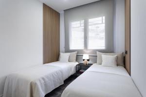 a row of three beds in a room with a window at ApartsNouBcn Equador Les Corts in Barcelona