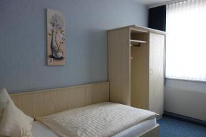 a room with a bed with a cabinet and a window at Hotel Lex in Hagen