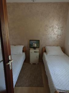 two twin beds in a room with a small table at Vikendica Budžak 51 - Apatin in Apatin
