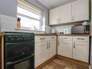 a kitchen with white cabinets and a black oven at Jubilee Cottage in Penzance