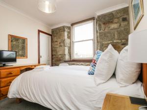 a bedroom with a large white bed with a stone wall at Jubilee Cottage in Penzance