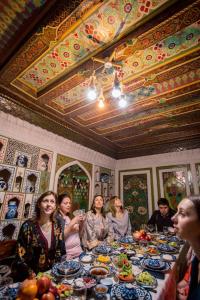a group of people sitting at a table with food at Fayz Guest House in Samarkand