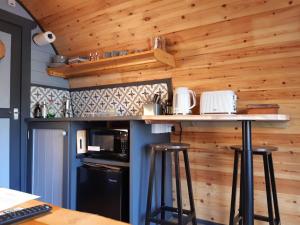 a kitchen with wooden walls and a counter with stools at Coe Pod, West Highland Way Holidays in Kinlochleven