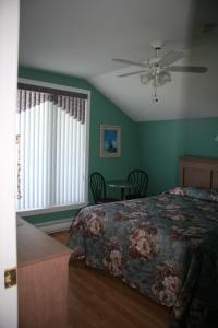 a bedroom with a bed and a ceiling fan at Escale de l'île - Auberge Janine du Havre in Shippagan