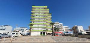 a tall apartment building with palm trees in a parking lot at Monte Gordo T2 Frente Mar in Monte Gordo