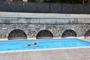 a person swimming in a swimming pool in a stone wall at Torre di Castelli - Menaggio by LoveComo in Menaggio