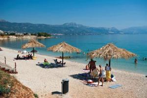 a group of people on a beach with umbrellas at Villa Isabella with private heated pool in Kaštela