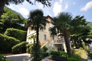 a house with two palm trees in front of it at Villa Angela Maria - Brienno by LoveComo in Brienno