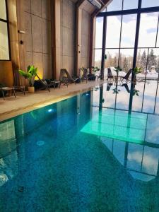 a large swimming pool with chairs in a building at Vardar 64 (Titova Vila) in Zlatibor