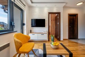 a living room with a table and a chair and a television at Vardar 64 (Titova Vila) in Zlatibor