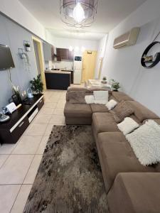 a living room with a brown couch and a kitchen at Carisa Holiday rooms in Larnaca