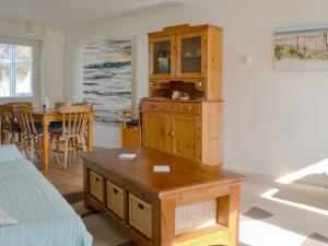 una sala de estar con un armario de madera y una mesa. en Beach House, en Sheringham