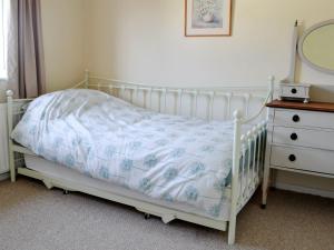 una cuna blanca en un dormitorio con tocador en Beach House, en Sheringham