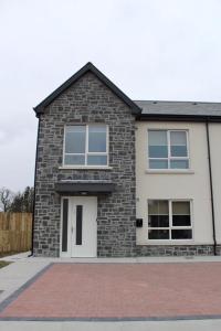 Casa de ladrillo con puertas y ventanas blancas en Bunratty west Townhouse en Bunratty