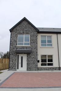 uma casa de tijolos com portas e janelas brancas em Bunratty west Townhouse em Bunratty