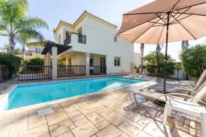 a swimming pool with an umbrella next to a house at Villa Lynn Chill Out Seaview in Ayia Napa