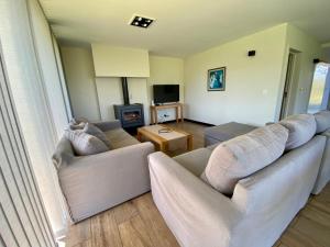 a living room with two couches and a television at Dpto de Categoría en Arelauquen Golf & Country in San Carlos de Bariloche