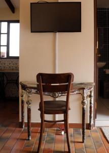 mesa de madera con silla y TV en la pared en Olala house en Sucre