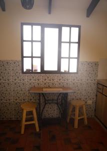 una mesa y dos taburetes en una habitación con ventana en Olala house en Sucre