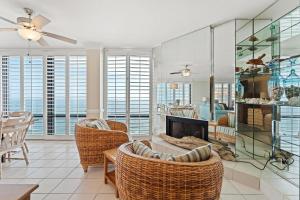 a living room with a fireplace and wicker chairs at Summer House 1501B in Orange Beach
