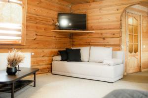 ein Wohnzimmer mit einer weißen Couch und einem TV an der Wand in der Unterkunft Viesu nams SAKNĪTES in Dzērbene