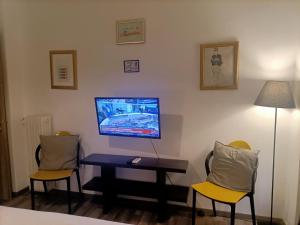 Zimmer mit 2 Stühlen und einem Tisch mit einem TV an der Wand in der Unterkunft Kallimarmaro Cozy in Athen