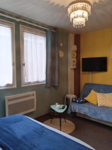 a bedroom with two beds and a tv and a chandelier at Studio Mer Centre équestre in Mers-les-Bains