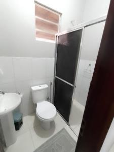 uma casa de banho branca com um WC e um chuveiro em Caju Hostel em Alter do Chão