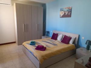een slaapkamer met een groot bed met paarse kussens bij Sunshine Holiday Apartment 4 Next to the Sea in St Paul's Bay