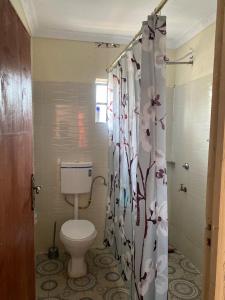 a bathroom with a toilet and a shower curtain with flowers at Razy's in Kakamega