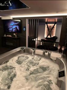 a large bath tub in a room with a tv at Loveroom Metz Spa Privatif in Metz