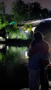 Évika boutique hotel في Eskilsby: حضان زوجين أمام النهر في الليل