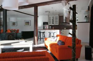 a living room with an orange couch and a kitchen at Näsets Marcusgård in Furudal