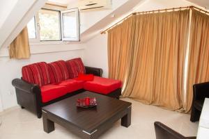 a living room with a red couch and a table at Attic flat ''Tsoukalas Group'' in Zakynthos Town