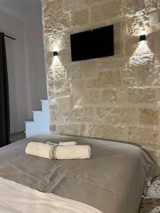 1 dormitorio con pared de piedra y 1 cama con 2 toallas en La PortaVecchia - #Home, en Monopoli
