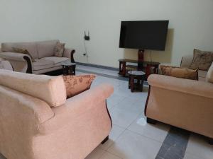 een woonkamer met banken en een flatscreen-tv bij Beautful Home Kigali-Kanombe in Kigali