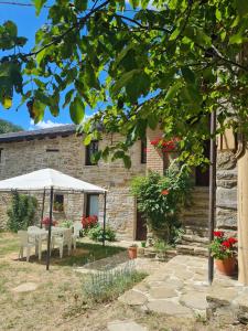 Casa de piedra con mesa y sombrilla blanca en Agriturismo Il Noce d'Oro, en Borgo Val di Taro
