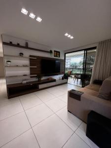 uma sala de estar com um sofá e uma televisão de ecrã plano em Mandara Lanai Apartamento Bangalô em Aquiraz