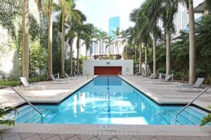 uma piscina com cadeiras e palmeiras em Center Stage- Downtown Parking Pool Hot Tub em Miami
