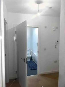 a white bathroom with a toilet and a doorway at Lovely one bedroom apartment with balcony in Forest Hill