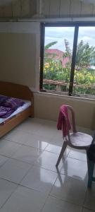 a room with a chair and a window and a bed at Karleta Homestay in Ruteng