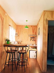 a kitchen with wooden walls and a table and stools at Cabañas Aulen Chepu Chiloe in Ancud
